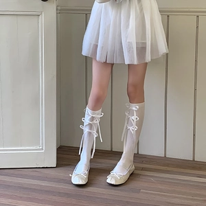 Detail van witte kniekousen in Balletcore-stijl met strikken en ballerina-schoenen