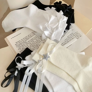 Détail de chaussettes Lolita blanches et noires avec nœuds et pendentifs étoile