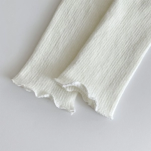 Détail du tissu en maille côtelée blanche avec finition délicate en bord ondulé