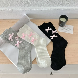 Detail of rib-knit socks in black, white, and gray with pink satin ribbon bows
