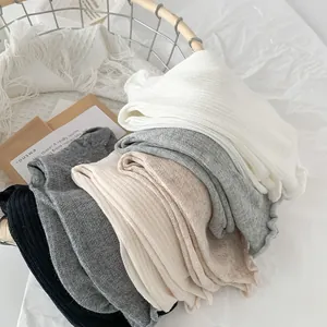 Close-up of ribbed cotton socks with ruffled edges in neutral tones inside a metal basket