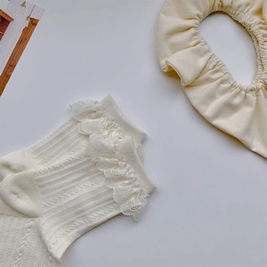Detailansicht von cremefarbenen Strickstrümpfen mit Spitzenbesatz und passendem Stirnband