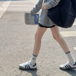 Detail of white mid-calf socks with black stripes and Three embroidery worn with sneakers