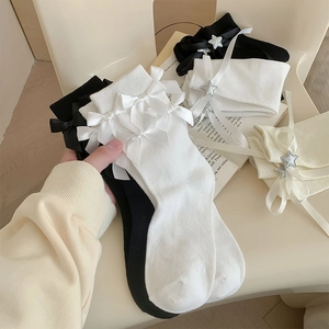 Gros plan de chaussettes mi-mollet Lolita avec nœuds en soie et breloques étoiles