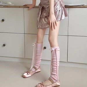 Gros plan sur jambières en tricot rose avec rubans de soie et nœuds style ballerine