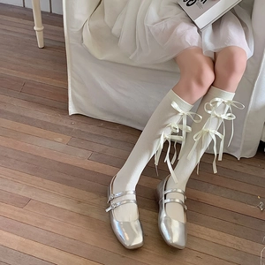 Detail van witte Lolita kniekousen met strikjes en zilveren Mary Jane lakschoenen