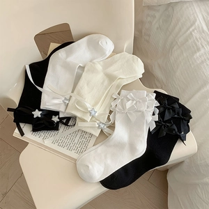 Détail de chaussettes Lolita blanches avec nœuds en satin et breloques étoiles