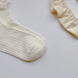 Nahaufnahme weißer gestreifter Baby-Spitzensocken mit plissiertem Stirnband