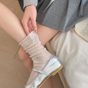 Detail of oatmeal ribbed socks with rolled edges paired with silver Mary Jane shoes