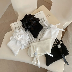 Détail de chaussettes Lolita blanches et noires avec nœuds en satin et breloques étoiles