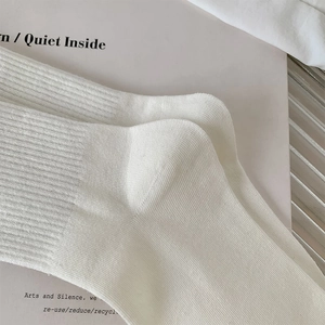 Close-up of white ribbed cotton mid-calf socks showing detailed knit texture and fabric quality