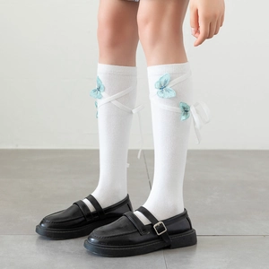 Detailed shot of white Lolita knee-high socks with blue butterfly embroidery and ribbon