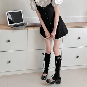 Détail de chaussettes hautes noires avec nœuds blancs et chaussures Mary Jane