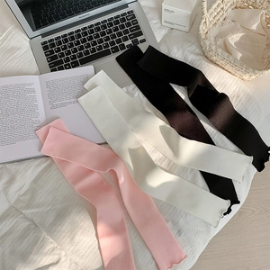 Detailed texture of knit leg warmers in pink, white and black with ruffled wavy edges