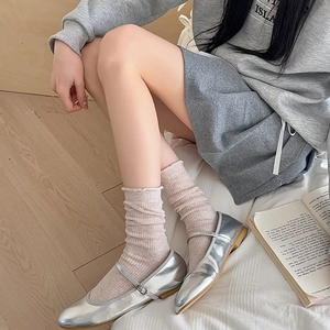 Detail of pink ruffled slouch socks paired with metallic silver Mary Jane shoes