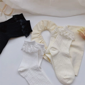 Detailansicht der Spitzenborte an gerippten Baumwollsocken in Schwarz, Weiß und Beige
