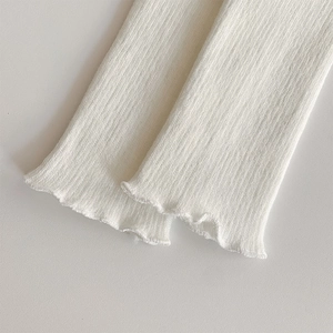 Detail of ribbed knit fabric texture with lettuce edge trim on cream leg warmers