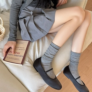 Detail view of grey ribbed knit slouch socks paired with black Mary Jane flat shoes