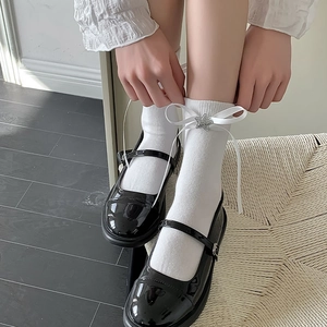 Gros plan de chaussettes Lolita blanches avec ruban et étoile sur chaussures vernies