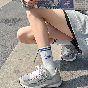 Detail of white cotton crew socks with blue stripes and Three embroidery on the side