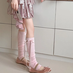 Gros plan détaillé de jambières en tricot rose avec rubans de soie et nœuds balletcore