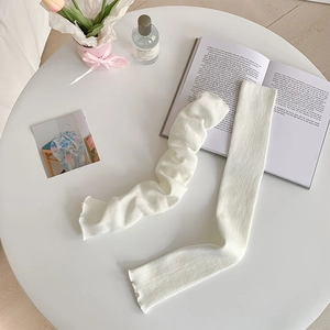 Close-up of cream white knit leg warmers with vertical stripes and ruffled edges