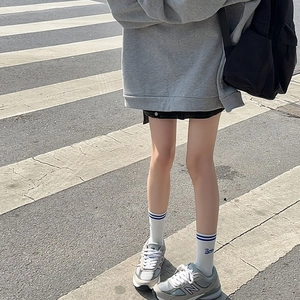 Detail showing white crew socks with blue stripes and embroidery in a street style outfit
