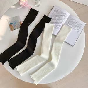 Close-up of knit texture on black and white leg warmers with vertical ribbed patterns