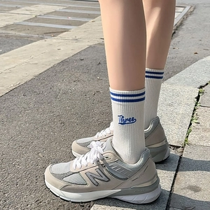 Detail of white ribbed mid-tube socks with blue stripes and Three embroidery on leg