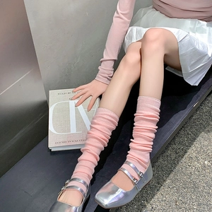 Detail of pink knitted slouch socks paired with silver Mary Jane shoes and a magazine