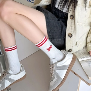 Close-up of white sporty crew socks with red double stripes and Three embroidery