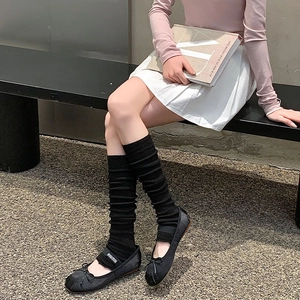 Detailed view of black knitted leg warmers paired with elegant ballet flat shoes