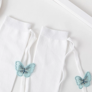 Detail of white Lolita socks featuring blue butterfly embroidery and silk ribbon ties