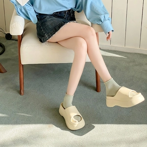 Close-up of white open-toe platform slides worn with light green socks for casual style