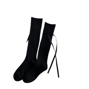 Black knee high socks with vertical stripes and silk bow decoration on white background
