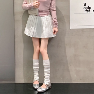 Detail shot of white slouch socks paired with silver Mary Jane shoes and a pleated skirt