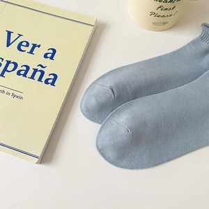 Close-up of light blue cotton knit socks with a soft rolled cuff on a white table