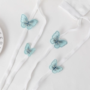 Detailed close-up of light blue butterfly embroidery on white elastic hosiery straps