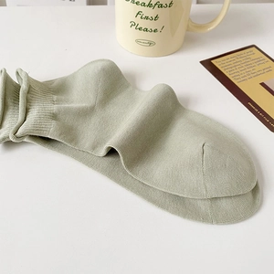 Detail view of sage green ribbed cotton blend socks with a stylish rolled cuff design