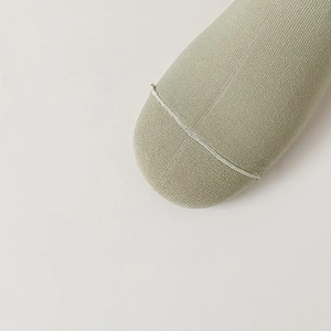Detail of light green knitted socks showing high-quality flat seam stitching and soft texture
