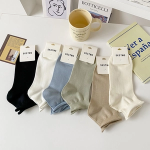 Flat lay of six pairs of solid color cotton ankle socks with rolled edge and rib design