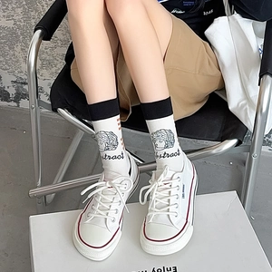 Close-up of white canvas sneakers and abstract art socks featuring classic bust patterns
