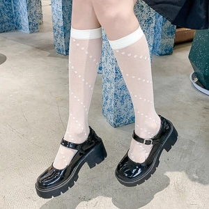 Detail of white polka dot sheer knee-high socks with black patent leather platform shoes