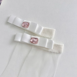 Close-up of white sheer mesh socks with satin bows and pink rhinestones in ballet style
