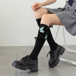 Detailed shot of black Lolita knee socks with blue butterfly embroidery and velvet bows