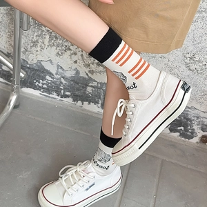 Detail of white canvas sneakers and mid-calf socks with abstract hand-drawn illustrations