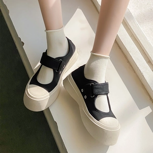 Detailed top view of black canvas Mary Janes with platform soles and white knit socks