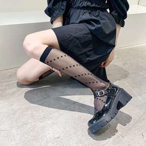 Close-up of black platform Mary Jane shoes paired with sheer polka dot knee-high socks