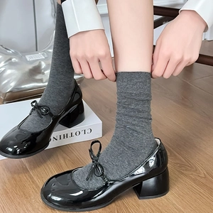 Close-up of black patent leather Mary Jane shoes with bows and grey crew socks