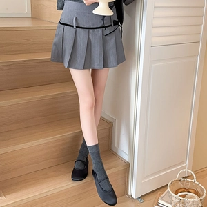 Detailed view of grey pleated skirt paired with cotton crew socks and Mary Jane shoes